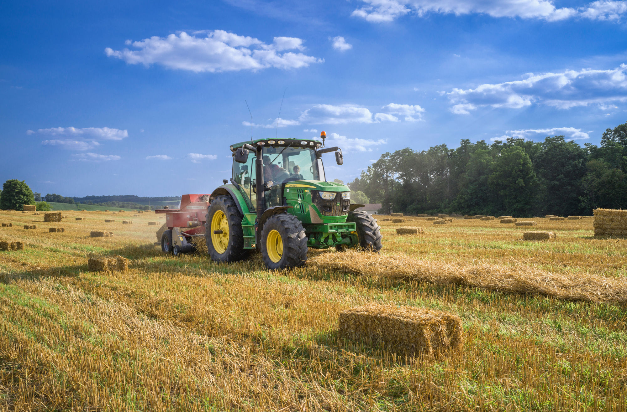 Traktor mit Ballenpresse bei der Strohernte