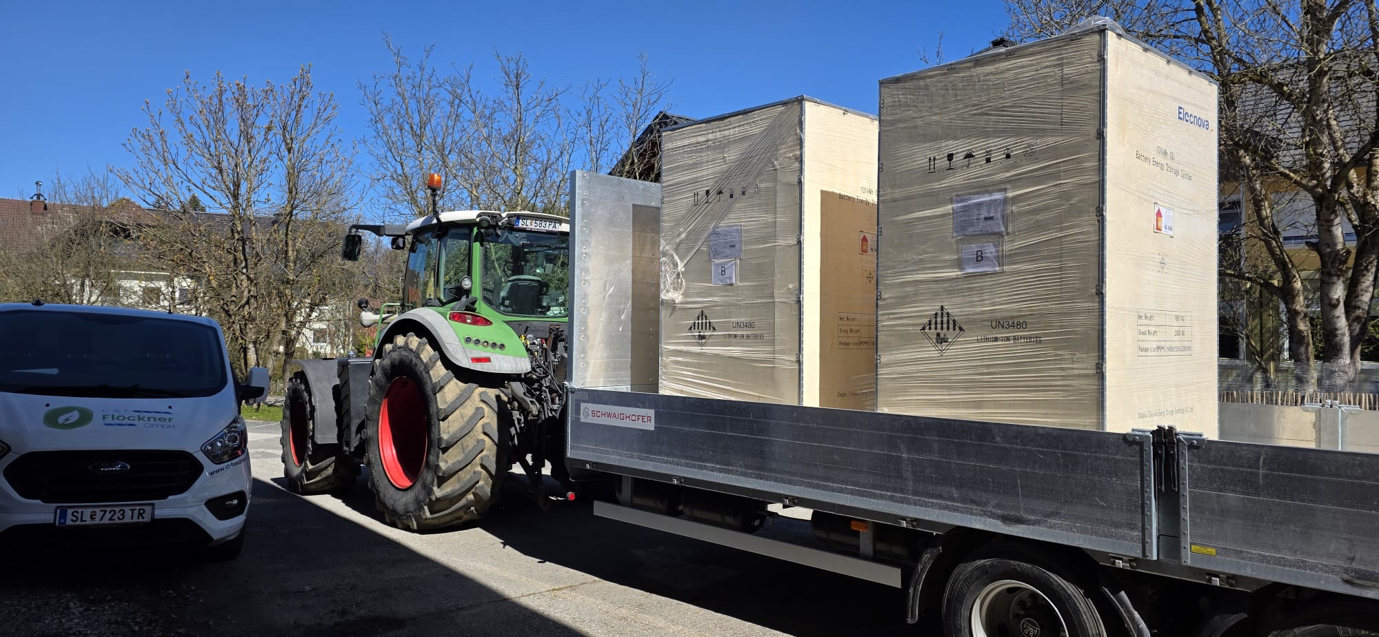 Traktor transportiert Batteriespeicher-Kisten am Hof